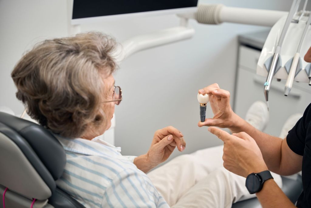 Older woman being shown physical example of a dental implant
